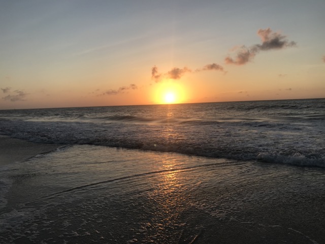 A serene sunrise at the beach, breaking over the horizon, casting warm light across the ocean, symbolizing new beginnings and the beauty of transitions.
