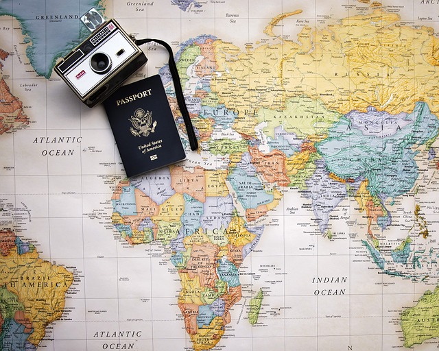 Travel items including passport and camera on top of a map, suggesting international travel.