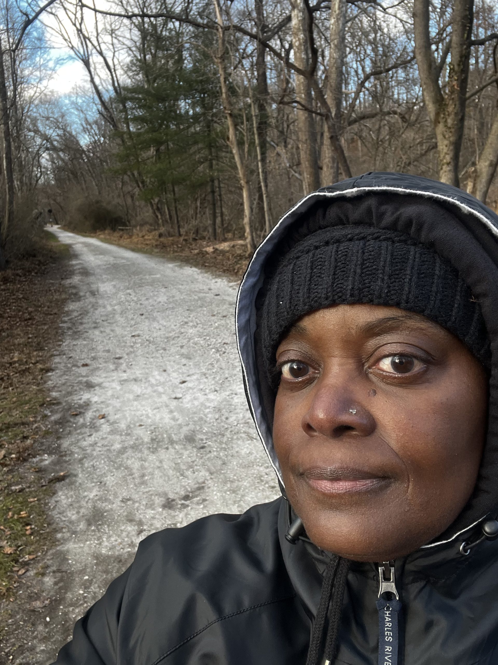 Woman walking on a nature trail in winter conditions, demonstrating perseverance and commitment to health goals