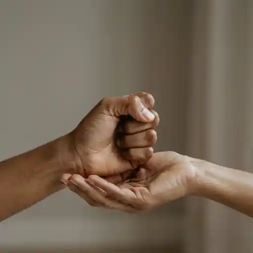 Close-up of two hands, one clenched and one open with palm facing up, illustrating the difference between holding on and surrendering.