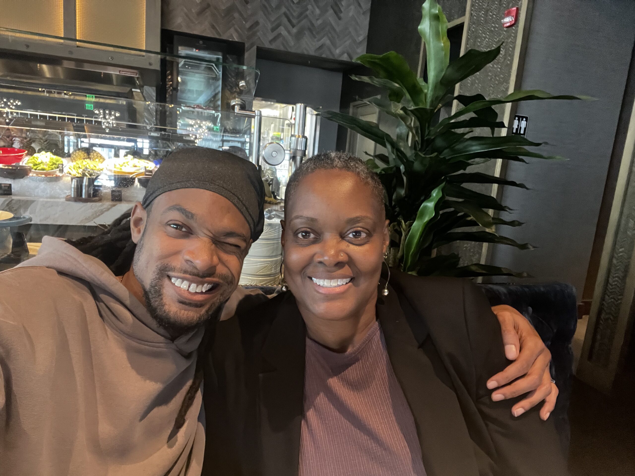 Tami Zanele smiling with her son at a restaurant dinner, celebrating her 56th birthday.
